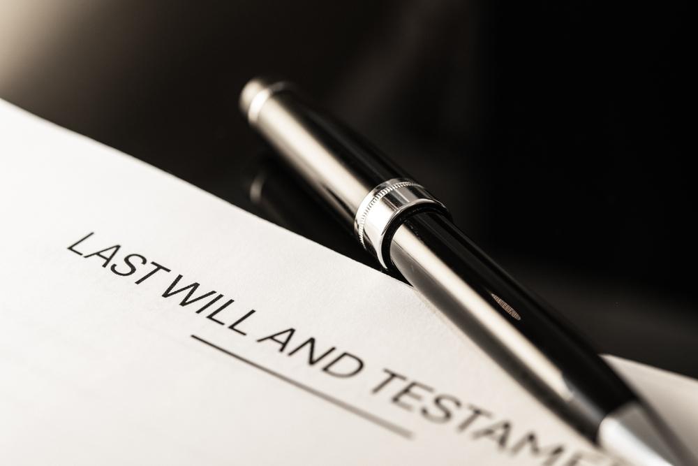Close-up of a last will and testament, with someone nearby interested in learning more about how to obtain a letter of testamentary.